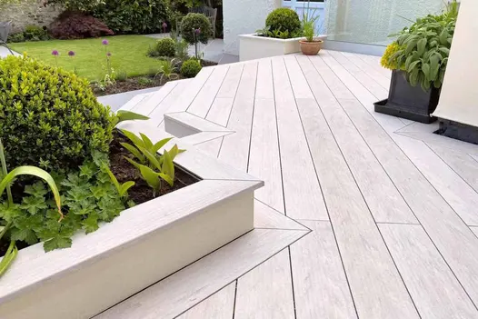 Silver DesignBoard composite decking with a pale grey timber-effect finish, installed in a contemporary garden with angular detailing around raised planters.