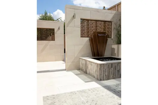A luxurious garden with bronze water feature and Allora Bianco 600x600 porcelain paving, adding a touch of elegance to the space.